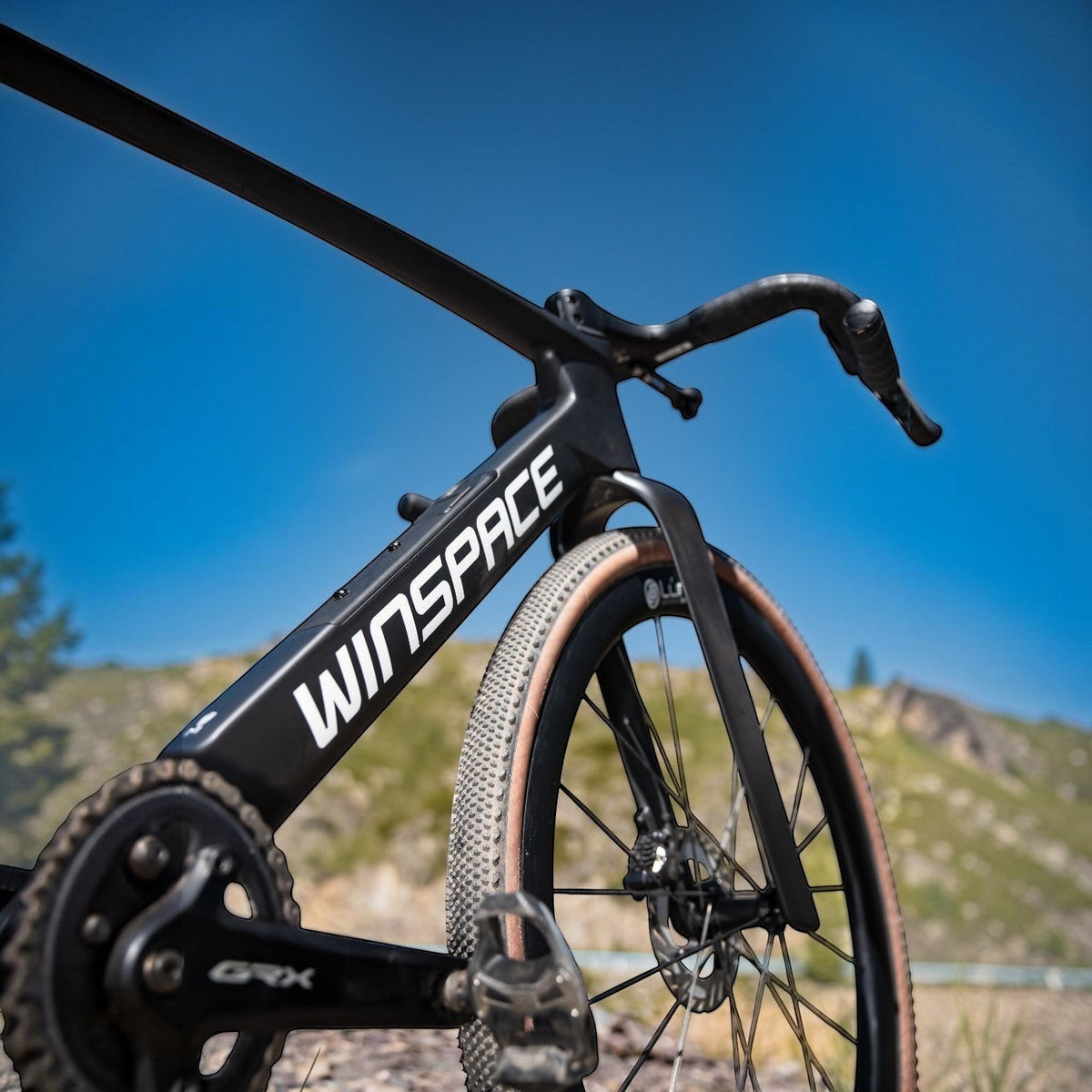 NorVelo G5 Gravel bike in matte black carbon with tan wall tires, featuring an aerodynamic frame and GRX components.