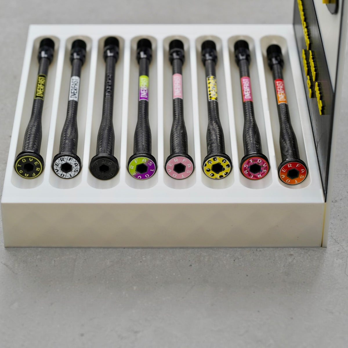 NorVelo OVERFAST ultralight carbon fiber thru axles with colorful aluminum threads and titanium inserts in a display tray
