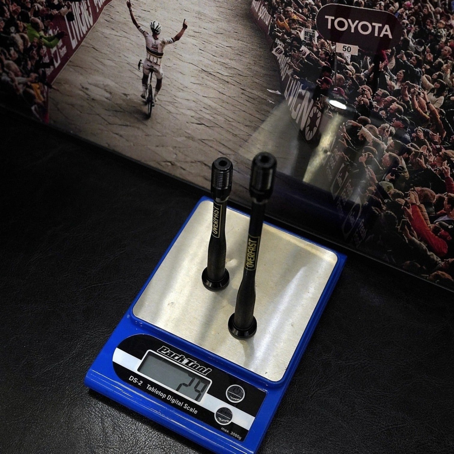 NorVelo OVERFAST ultralight thru axles with carbon shafts and titanium inserts displayed on a digital scale