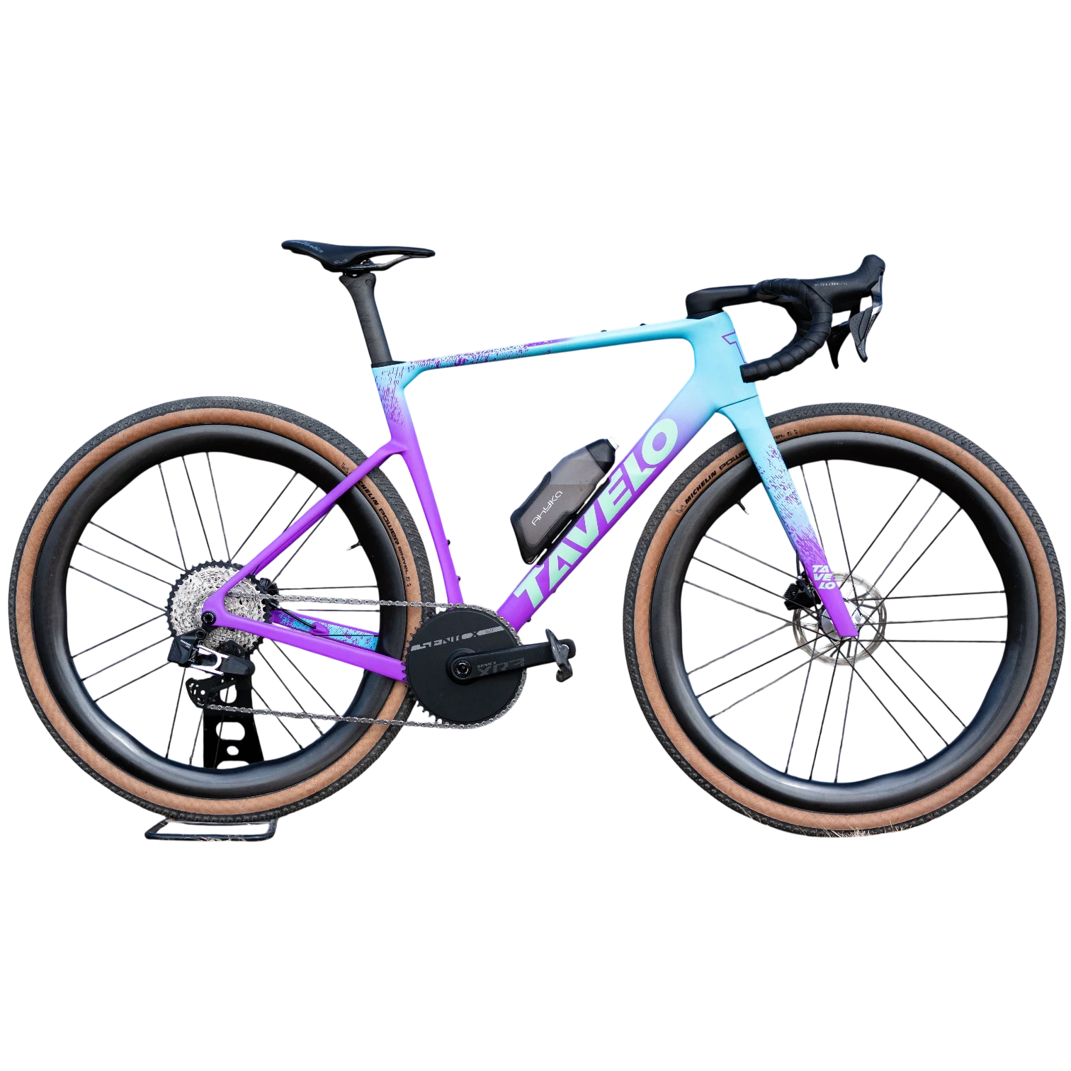 NorVelo Tavelo Grow aero gravel bike with a purple and blue gradient carbon frame, tan wall tires, and FIDLOCK storage.